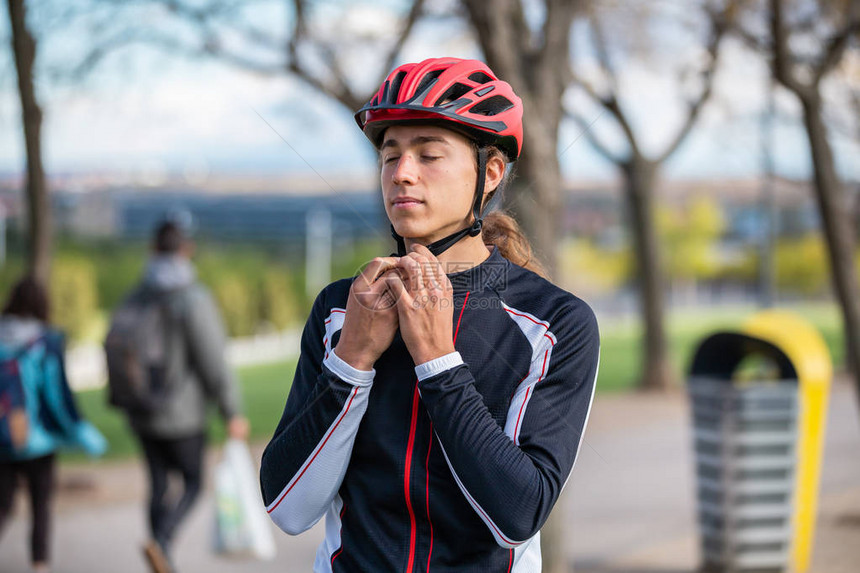 年轻英俊的男骑自行车运动员在美丽的城市公园穿运动图片