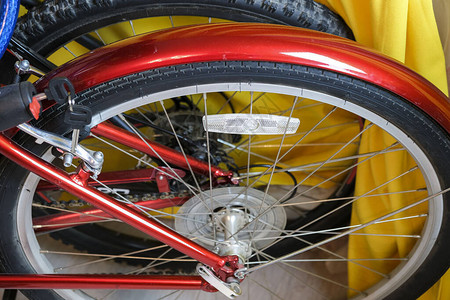 红色亮闪的自行车后轮靠着黄色窗帘背景图片