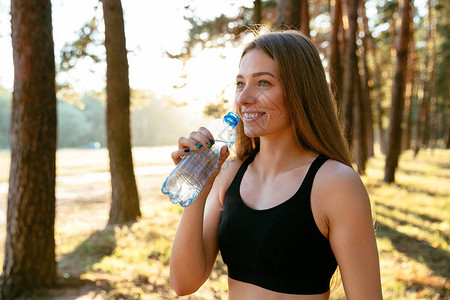 体育女青年在公园跑步后喝瓶装水的户外照片图片