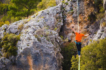 一个人正沿着一条拉长的吊索行走山中的高线人抓住平衡走钢丝者在大自然中的表现Highliner背景图片