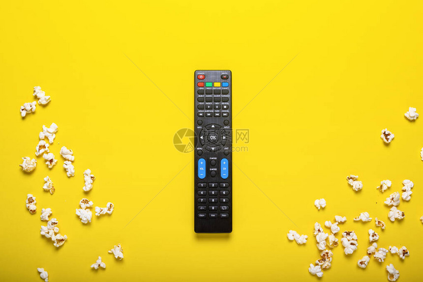 黄色背景上带有爆米花的电视电视调谐器或音频系统的黑色遥控器图片