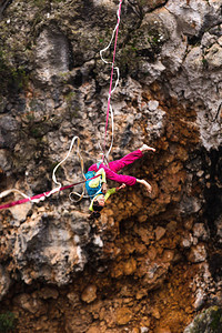 女孩落在一个拉伸的吊索上山中的高线女人失去了平衡自然界中的演讲走钢丝者Highliner挂在绳子上背景图片