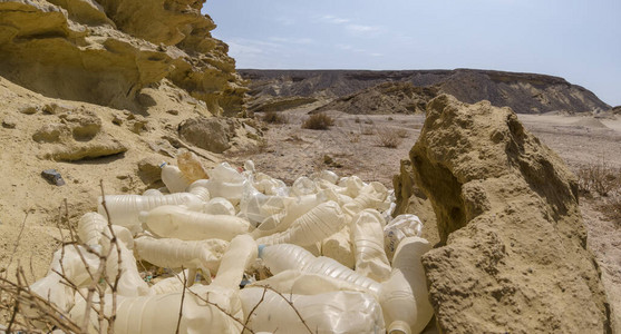 旧塑料瓶倾倒在沙漠中的沙漠中图片