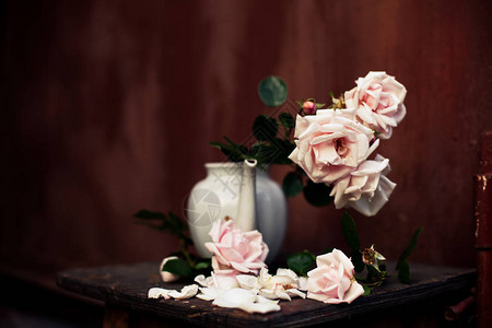 白色茶壶花瓶中的淡粉色玫瑰花束图片