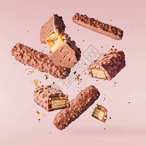 巧克力和焦糖在空气中飞动的巧克力在粉色糊面背景上隔离高分辨率图像图片
