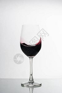 浓郁的深红葡萄酒在反光表面的优雅酒杯中旋转图片