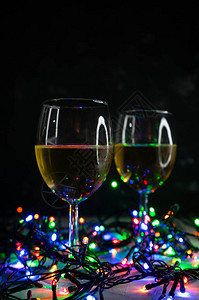 在圣诞节彩色灯泡的光照下透明葡萄酒杯图片