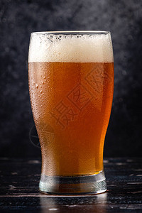 深色背景中带水滴的啤酒杯背景图片