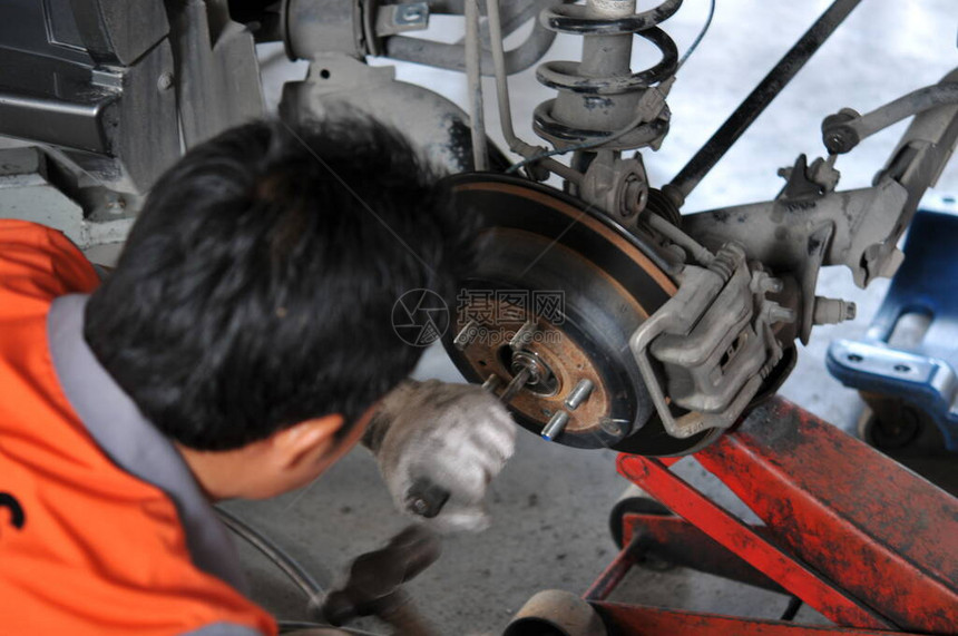 新轮胎更换过程中的汽车修理工车库中的汽车制动器维修带拆卸车轮的汽车上的制动器车库的汽车制动部件无车轮图片
