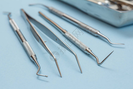 一套用于牙科治疗的金属牙科器械蓝色背景上的牙科塞子镊子探针和刮刀医疗图片