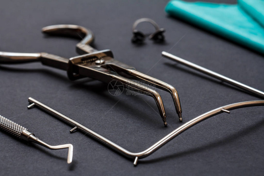 一套牙科治疗仪器黑色背景上用于扣子围堰框架刮刀和手帕的牙科钳医疗图片