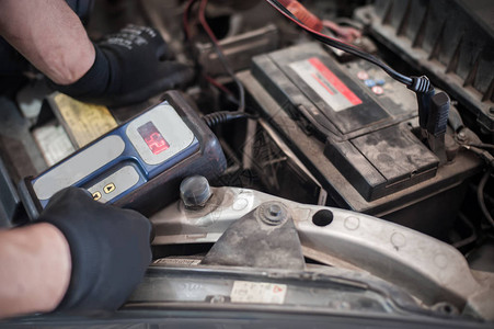 汽车修理工在汽车间用数字电子池测试仪和分析仪检查和测背景图片