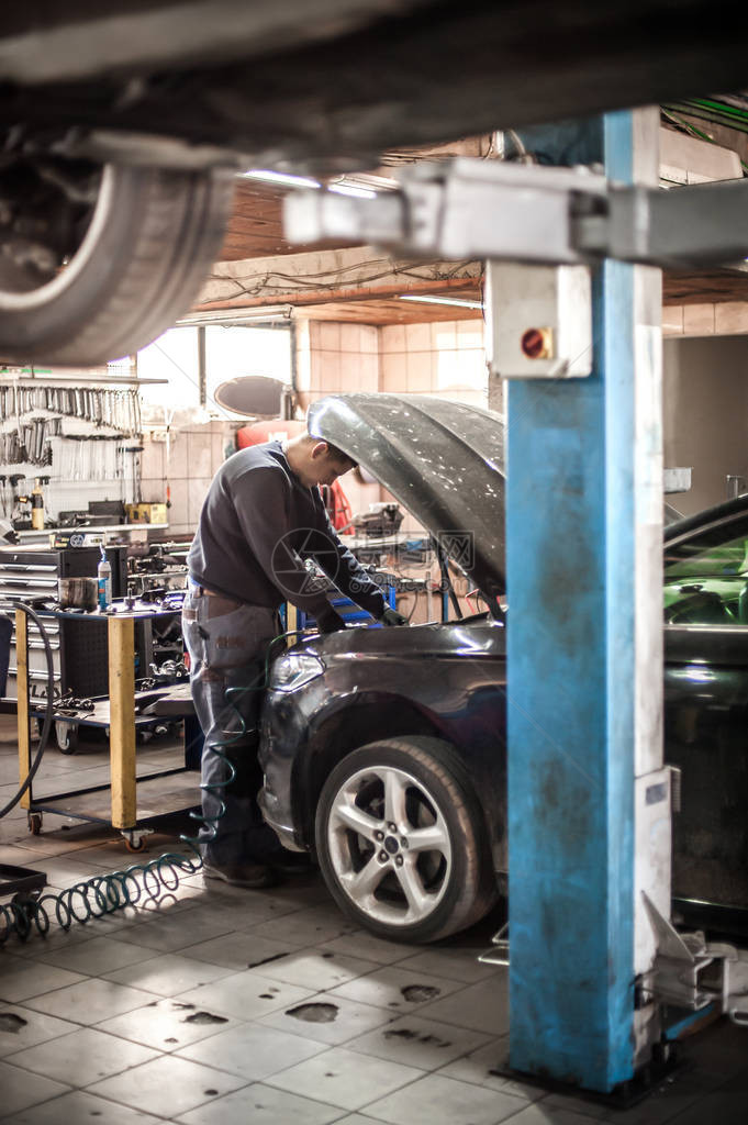 汽车大师汽车修理工维修技师在汽车维修店的引擎盖下检查和维图片