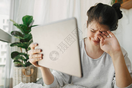 悲伤的女孩因平板电脑的坏消息而哭泣图片