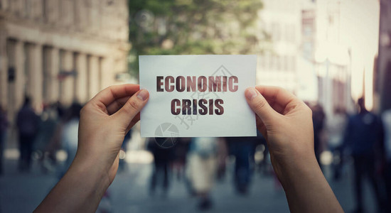 手拿着一张纸警告全球经济危机概念在拥挤的街道背景图片