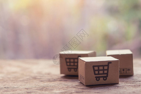 网上购物纸盒或木桌上带有购物车标志的包裹网上购物服务并提供图片