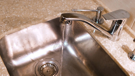 水从厨房水龙头流入金属水槽干净的水从厨房的镀图片
