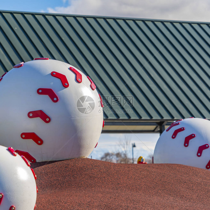 在操场棕色丘陵上方的广场巨型棒球装饰可以在背景中看到球馆和阴云蓝图片