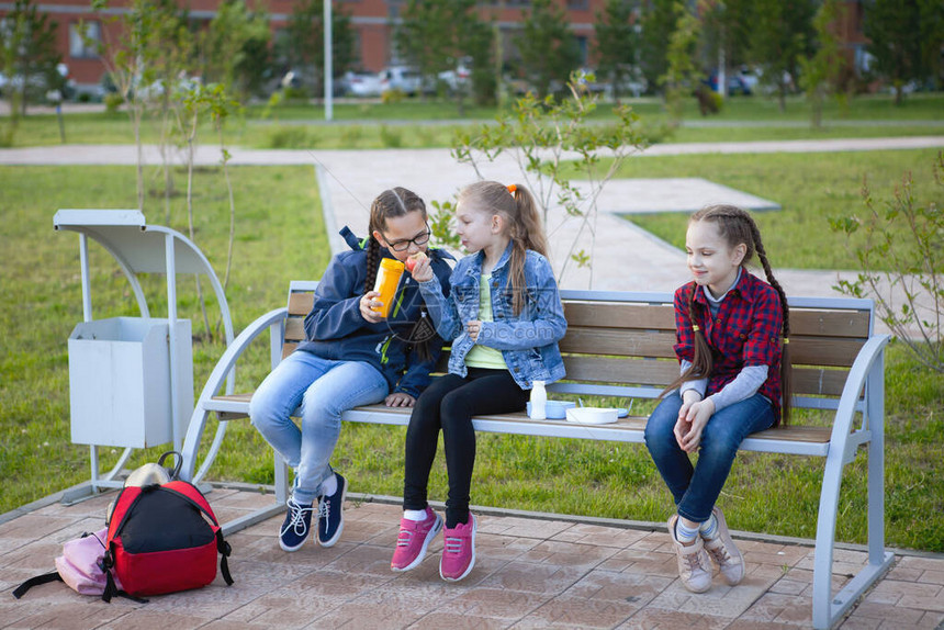 青少年女孩在城市公园的长椅上吃饭图片