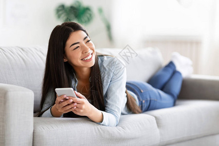 亚洲无忧虑的亚裔女士享受用智能手机在与朋友通信时轻笑自由空间等舒适的图片