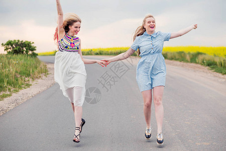 两个女孩手牵着手在路上奔跑的照片图片