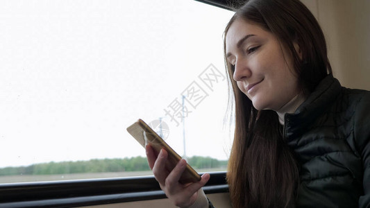 年轻的黑发女旅行者的肖像正在智能手机上看东西图片