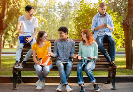 多种族学生下课后坐在公园户外长椅上放松大学图片