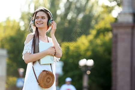 美丽的年轻女子在户外听有声读物图片