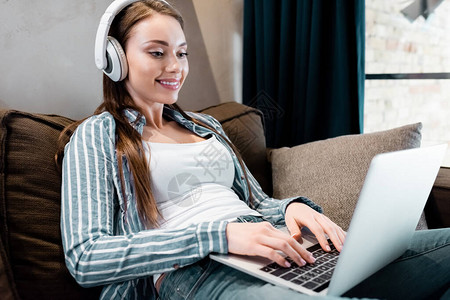 使用客厅膝上型电脑无线耳机的快乐自由职业图片