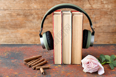 桌子上的书籍现代耳机糖果和鲜花有声读物的概念图片