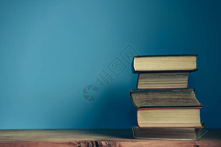 旧的红色木桌和蓝色墙壁背景上的漂亮打开书籍图片