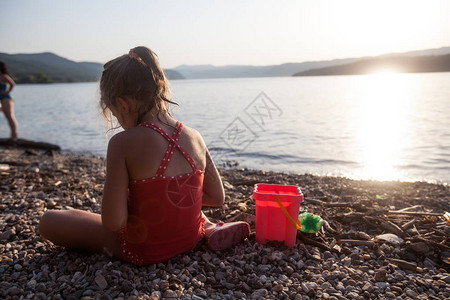 看着小女孩在日落时在河岸玩耍阳光图片