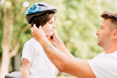 父亲把头盔戴在儿子的一面而图片