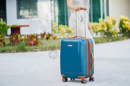 游客的蓝色手提箱由女手持图片