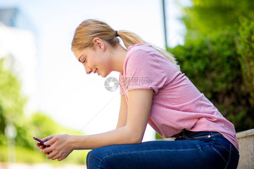坐在外面看手机的少女侧面肖像图片