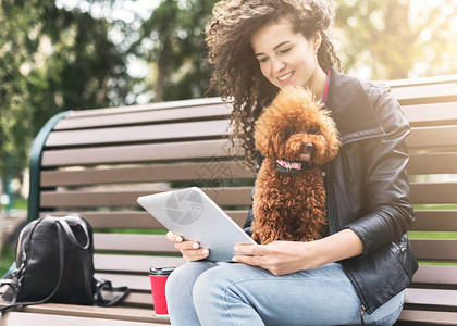 可爱的女人和她的小狗一起在城市公园的长椅上网图片