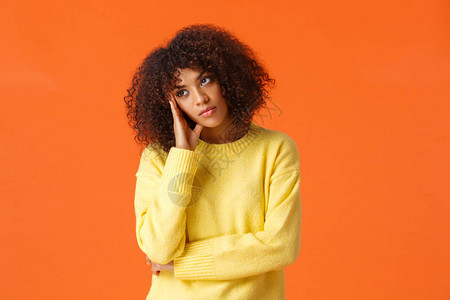 身穿黄色毛衣捂脸不感兴趣怀疑的表情看着别处的无聊的非洲裔美国女图片