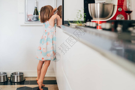 饥肠辘的女婴无法抗拒地在冰箱里踮着脚尖寻找食物图片