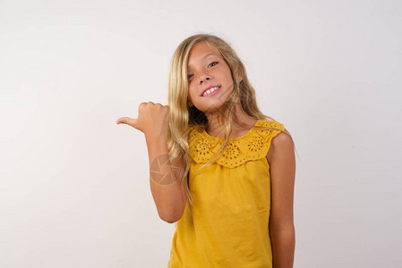 可爱的小女孩用拇指向一边在背景图片