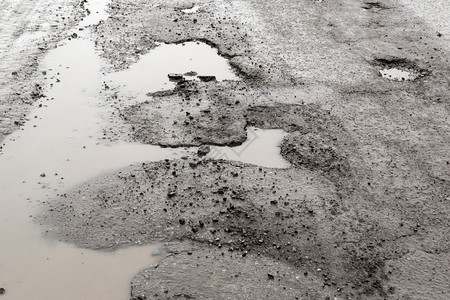 填满泥积雨水的破沥青马路大坑洞图片