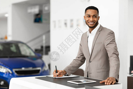 汽车销售商男子站在经销商办公室的办公桌前汽车销售业务选择焦点图片