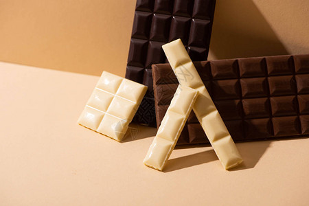 米色背景上甜美可口的黑巧克力牛奶巧克力和白巧克力图片