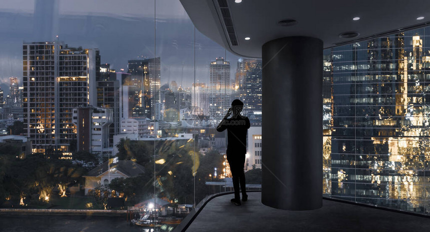 商人站在现代空间使用智能手机观看城市夜景图片
