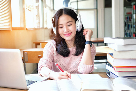 在图书馆学习时心情好听音乐的女青年背景