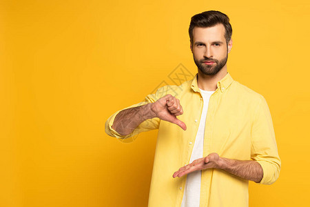 男子在黄色背景上用手语表示手势时图片