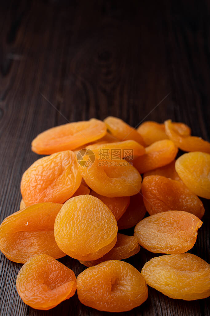 深色木桌上一堆鲜橙色的杏干特写图片