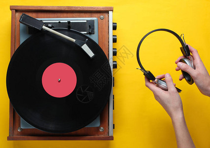 Retro风格乙烯唱片播放机和手持耳机最小化黄色背景的顶视图图片