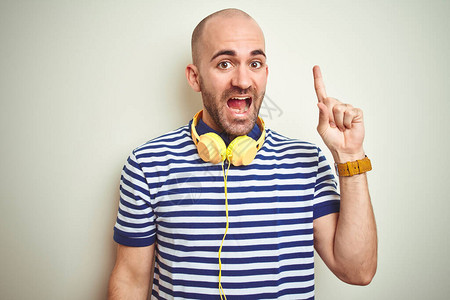 年轻人戴着黄色耳机在孤立的背景下听音乐图片