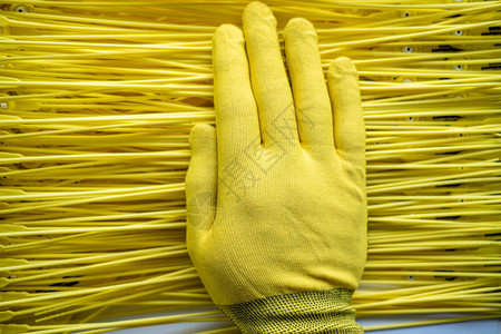 在塑料线的黄色背景之上是一只戴着黄色手套的手图片