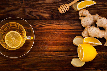一杯加柠檬蜂蜜和姜根的姜茶放在木制背景上复制空图片